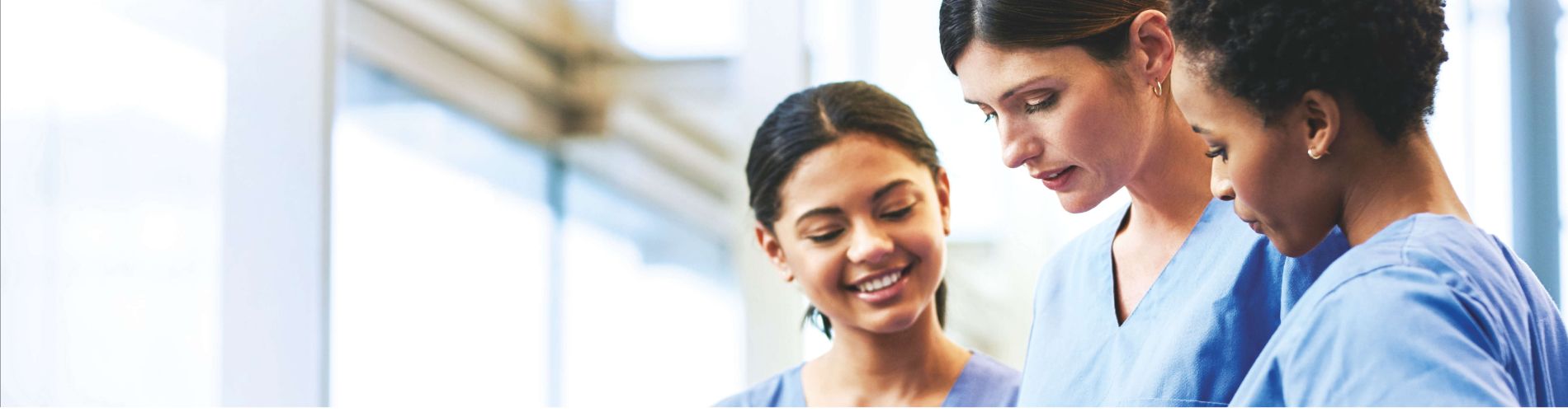 3 healthcare workers, nurses, standing in bright room, talking, looking at tablet, QFT
